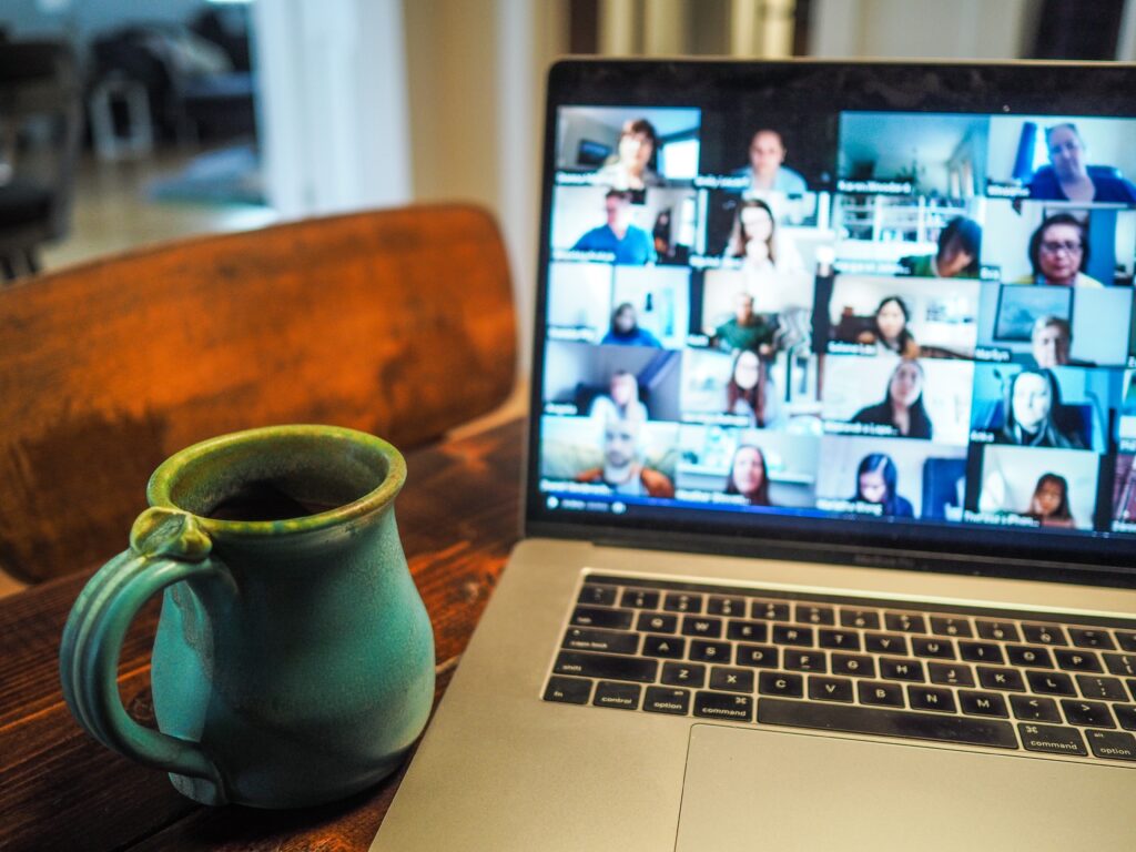 laptop screen with lots of faces on it in a zoom meeting